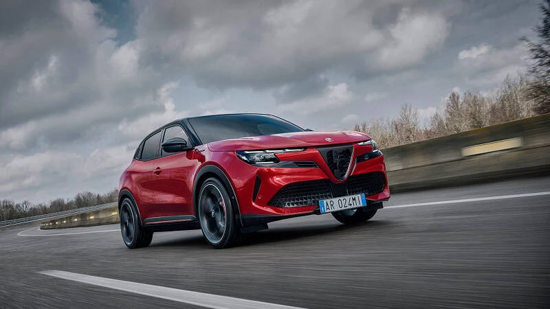 Červené Alfa Romeo Junior Veloce v jazde na okruhu pod zamračenou oblohou