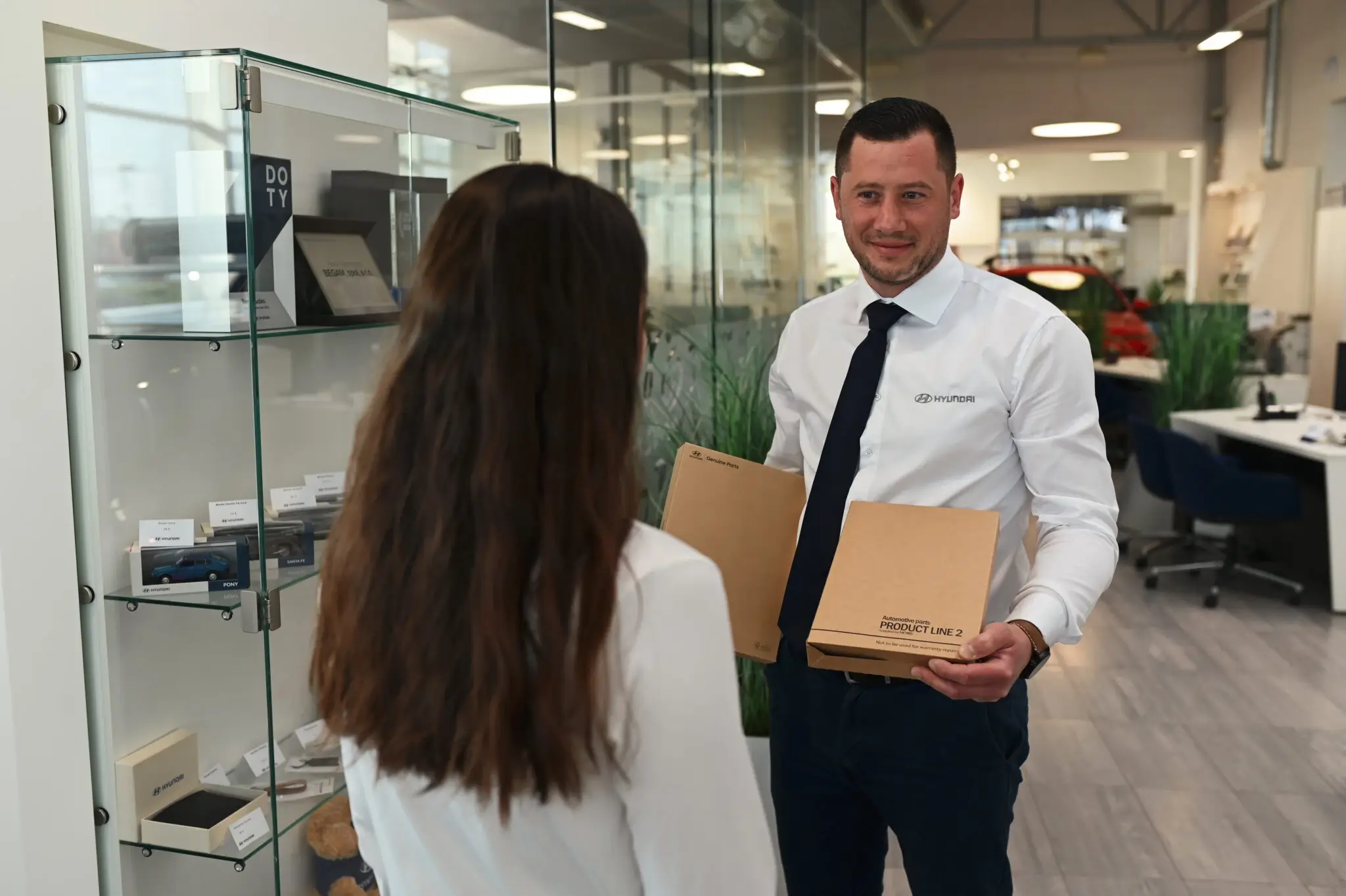 Servisný poradca Hyundai odovzdáva zákazníčke originálne náhradné diely v autorizovanom servise BEGAM Trnava