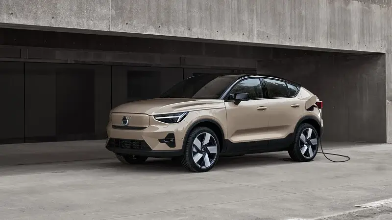 Volvo EC40 v zlatistej farbe počas nabíjania pri nabíjacej stanici – plne elektrické SUV kupé pripojené do siete