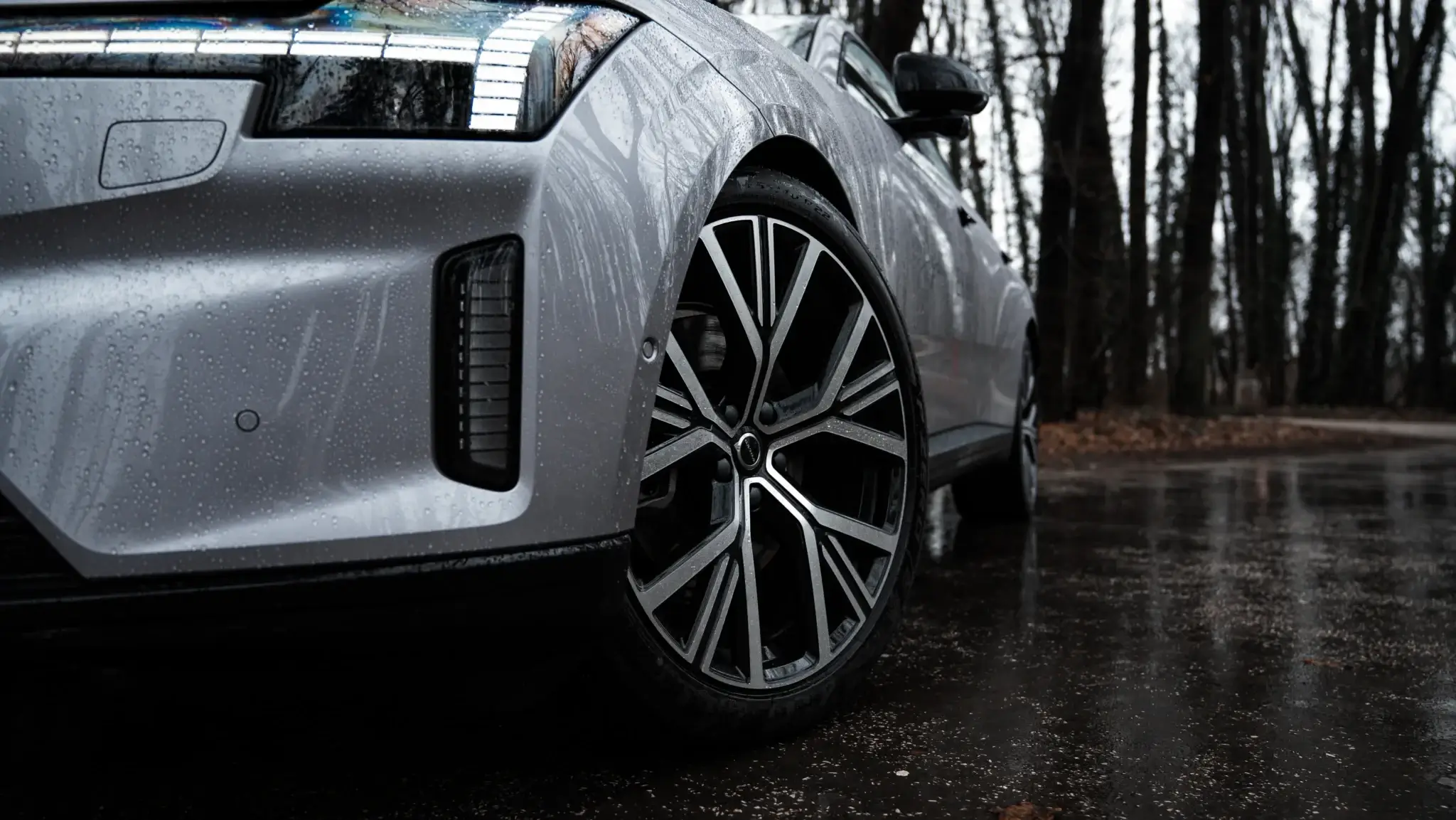 Detail predného kolesa Volvo ES90 s aerodynamickým diskom a pixelovými LED svetlami na mokrej ceste