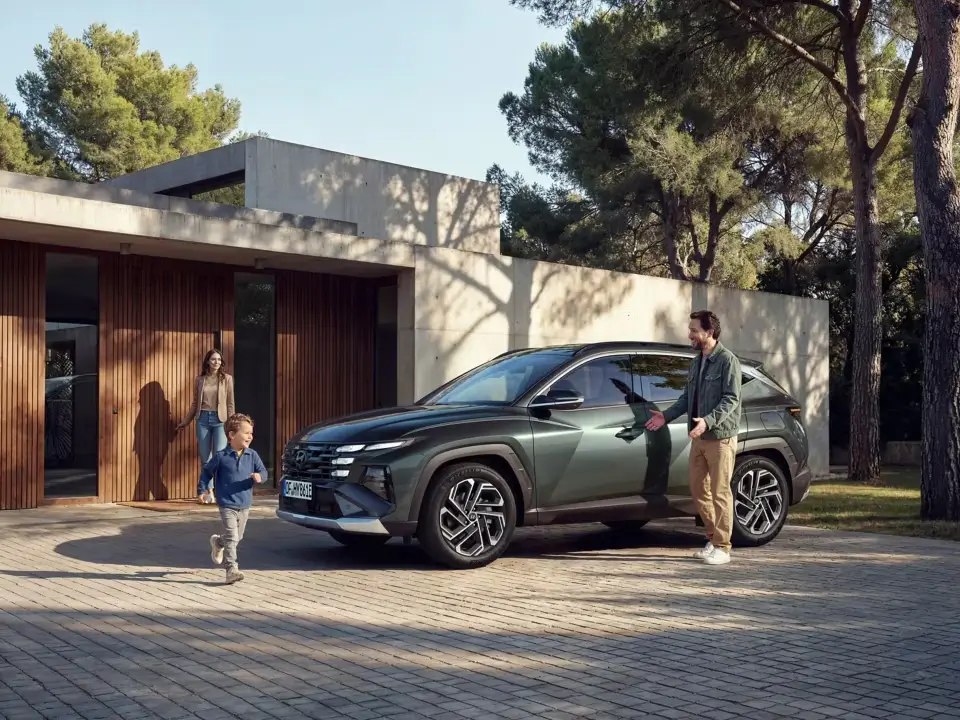 Zelený Hyundai Tucson pred moderným rodinným domom s otcom, mamou a synom v ponuke BEGAM Trnava