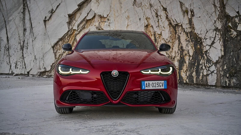 Priamy čelný pohľad na červenú Alfa Romeo Giulia s maskou Scudetto v mramorovom lome