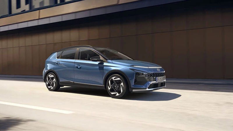 Modrý Hyundai Bayon v jazde po mestskej ceste, bočný trojštvrťový pohľad
