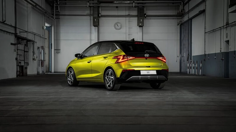 Žltý Hyundai i20 s čiernou strechou, zadný pohľad v industriálnej hale