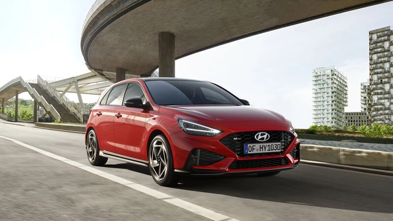 Červený Hyundai i30 N Line v jazde po ceste pod diaľničným nadjazdom