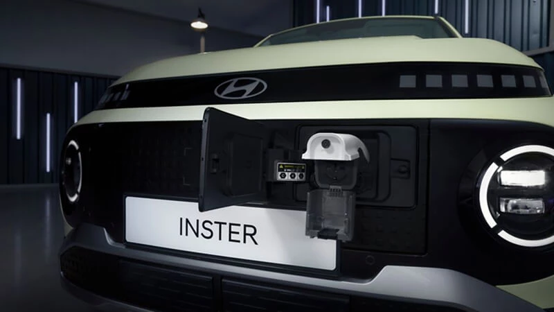Detail otvoreného nabíjacieho portu na prednej maske žltozeleného Hyundai Inster