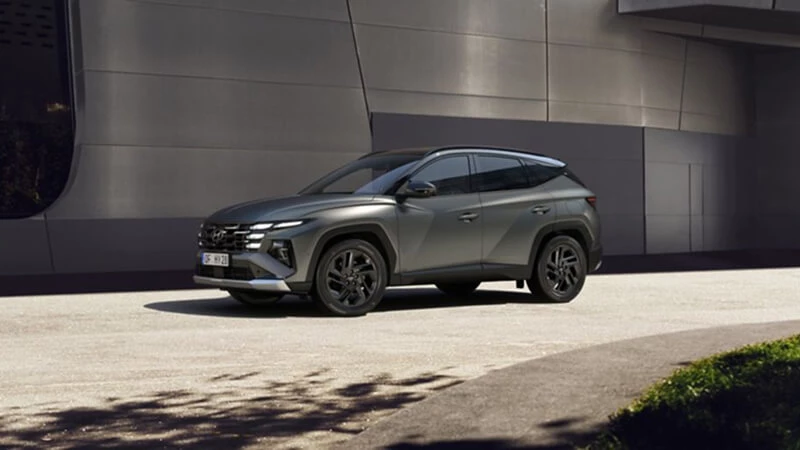 Tmavozelený Hyundai Tucson facelift zaparkovaný pred modernou sivou fasádou